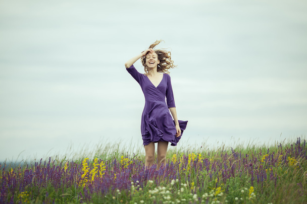 Chica joven en vestido vintage caminando por el campo de flores de salvia
. - Foto, Imagen