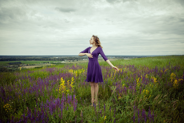 Giovane ragazza in abito vintage a piedi attraverso il campo di fiori salvia
. - Foto, immagini