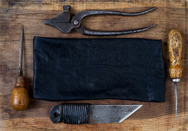 Leather craft tools on a wooden background. Craftmans work desk. - 写真・画像