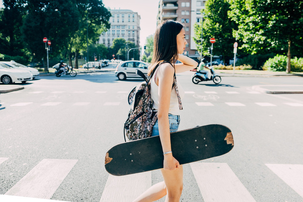 woman walking holding a skateboard  - Photo, Image
