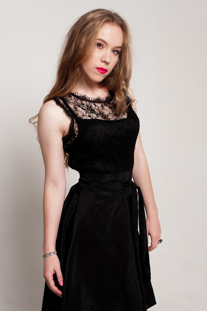 Portrait of beautiful young blonde girl in black dress. Fashion photo - Фото, зображення