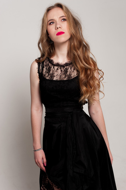 Portrait of beautiful young blonde girl in black dress. Fashion photo - Zdjęcie, obraz