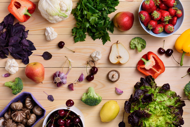 Variety of colorful fruits, vegetables and berries. Healthy diet concept. Vegetarian organic food set over wooden table. Top view.  - Photo, image