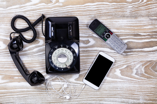 Teléfono retro con modernos dispositivos de comunicación en madera descolorida
  - Foto, Imagen