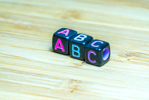 Cubo de letras de colores con superficie de textura de bambú. Cooperación educativa
 - Foto, imagen