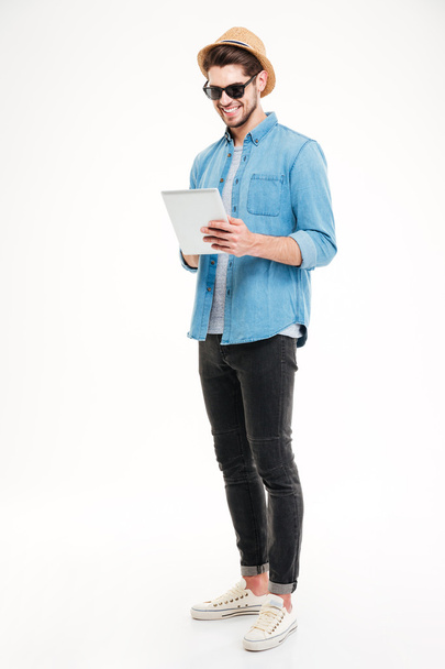 Πλήρες μήκος του ευτυχισμένο όμορφο νεαρό άντρα χρησιμοποιώντας tablet - Φωτογραφία, εικόνα