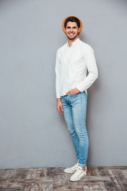 glücklich schöner junger Mann in weißem Hemd, Jeans und Hut - Foto, Bild