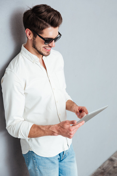 Portrait of a happy man in sunglasses using tablet computer - Фото, изображение
