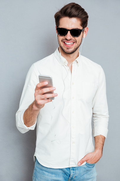 Portrait of a casual smiling man using smartphone - 写真・画像