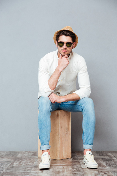 Pensive young man in sunglasses sitting and thinking - Photo, Image