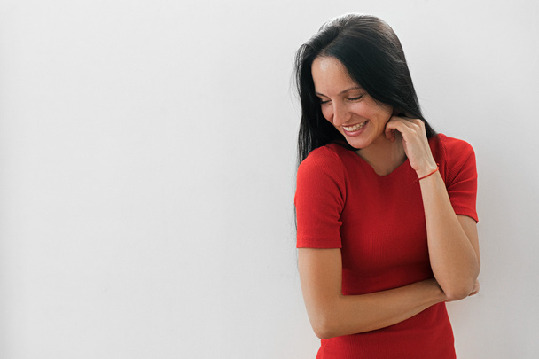 Shy black-haired woman smiling against of white background - Zdjęcie, obraz