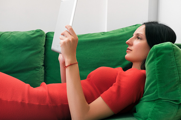 Woman using tablet on green sofa  - Zdjęcie, obraz