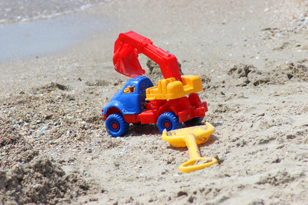 Zabawka samochód ekskovator i łopata na piaszczystej wybrzeżu - Zdjęcie, obraz