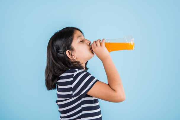 indian girl with cold drink bottle, asian girl drinking cold drink in pet bottle, girl kid and cold drink, indian cute girl with mango or orange cold drink in plastic bottle, isolated - Fotó, kép