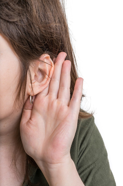 Mujer sostiene su mano cerca de la oreja y escucha cuidadosamente
. - Foto, imagen