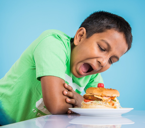 cute indian boy and burger in small white plate, small asian boy and burger, over colourful background - Photo, Image