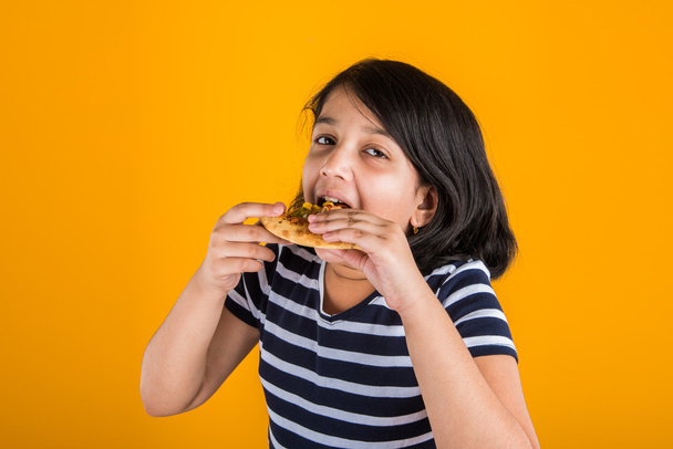csinos indiai lány pizzát eszik mint sárga háttér portréja - Fotó, kép