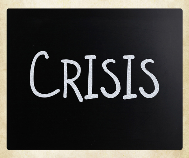 "Crisis"handgeschreven met wit krijt op een bord. - Foto, afbeelding