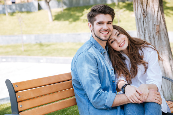 Feliz joven pareja enamorada sentada en un banco del parque
 - Foto, imagen