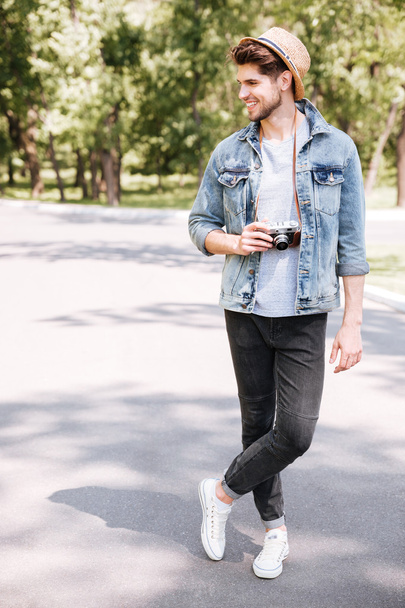 Handsome hipster guy holding camera wearing hat outdoors - Fotoğraf, Görsel