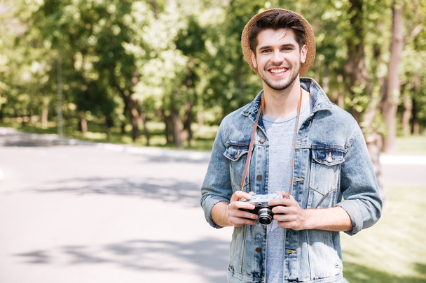 Happy young man in hat with old vintage photo camera - 写真・画像