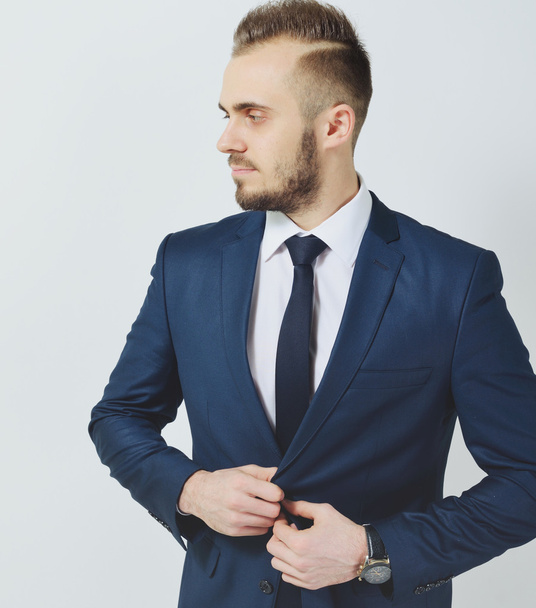 Successful businessman. Portrait of confident young man in formalwear looking at camera and smiling while keeping arms crossed and standing against grey background - Fotografie, Obrázek