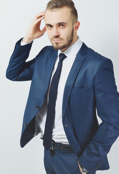 Successful businessman. Portrait of confident young man in formalwear looking at camera and smiling while keeping arms crossed and standing against grey background - Photo, Image