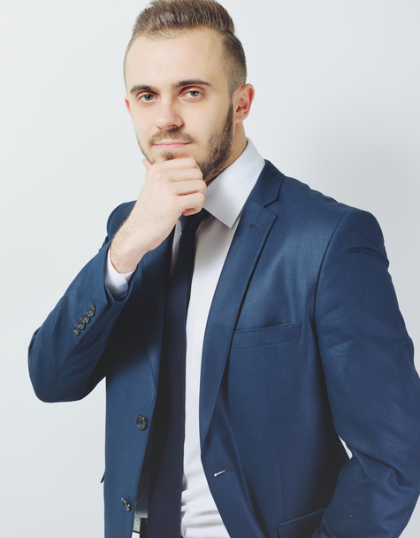 Successful businessman. Portrait of confident young man in formalwear looking at camera and smiling while keeping arms crossed and standing against grey background - Foto, Bild
