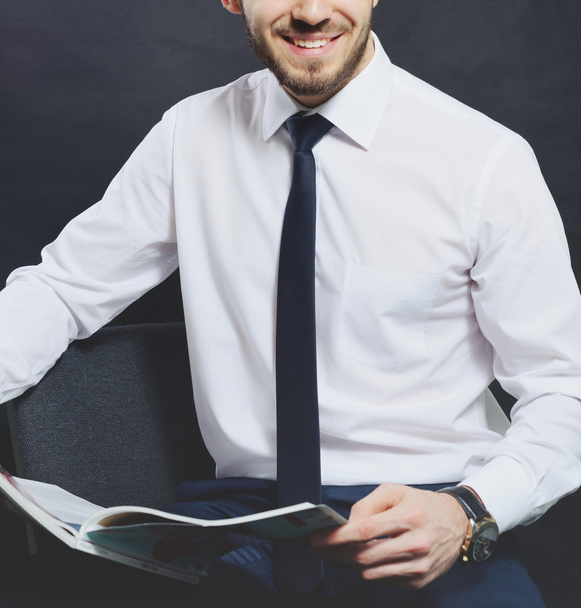 Successful businessman. Portrait of confident young man in formalwear looking at camera and smiling while keeping arms crossed and standing against grey background - Foto, Bild