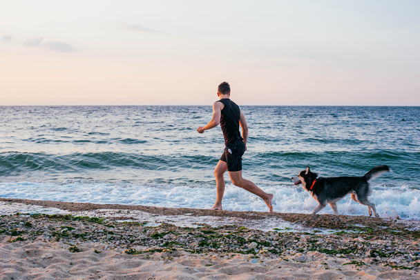 Man running with dog on beach - Fotografie, Obrázek