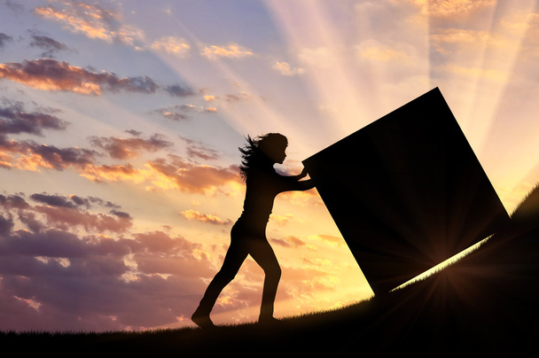 Silhouette of strong woman pushing a cube to the top. - Photo, Image