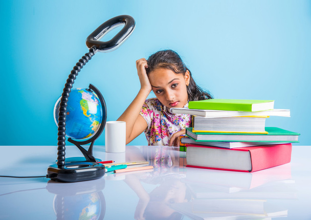 education and home concept - stressed student girl with books, indian girl child tired of studying or doing homework, asian girl studying and stressed, with globe toy and coffee mug - Photo, Image