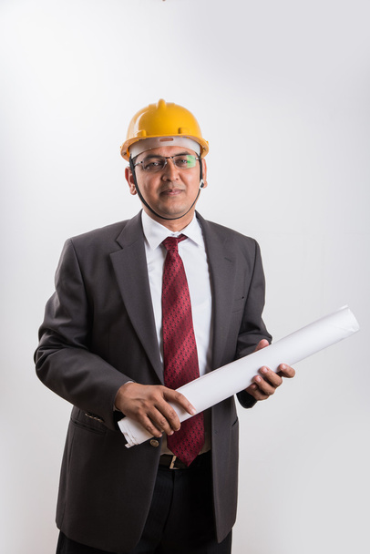 indian businessman holding a blueprint, wearing yellow hard hat, isolated over white background - Photo, image
