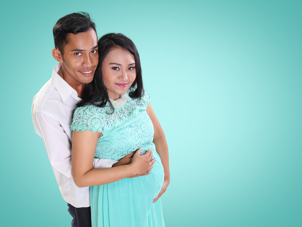 Lovely family during maternity over mint color background - Photo, Image