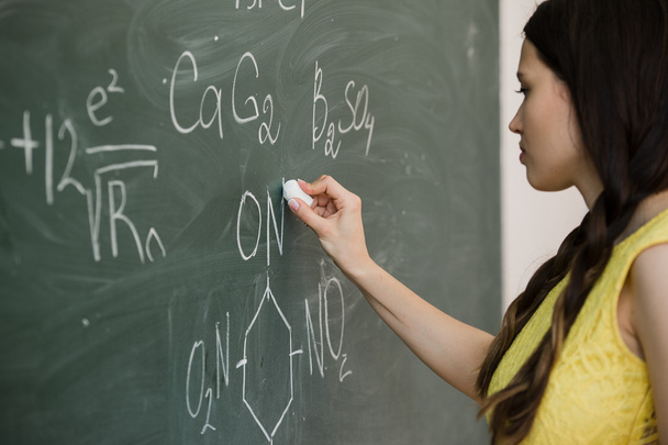 pretty young female college student writing on the chalkboard blackboard during a chemistry class - Photo, Image