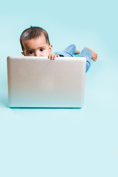 baby sitting on the floor with a laptop, indian baby girl with laptop over blue background, indian baby girl playing with laptop, asian baby girl with laptop - Fotó, kép