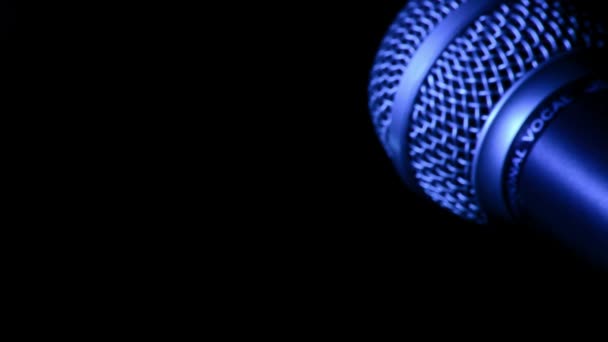 Mikrofon z niebieskim światłem obrotowy na czarnym tle - Materiał filmowy, wideo