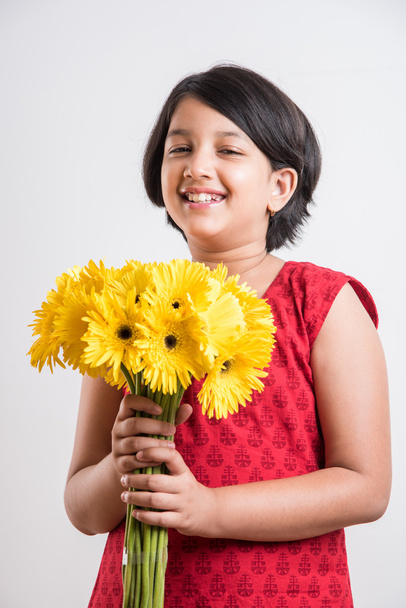 indian small girl holding bouquet of yellow gerbera flowers, isolated over white background, indian girl and flowers, asian girk holding flowers - Foto, Imagen