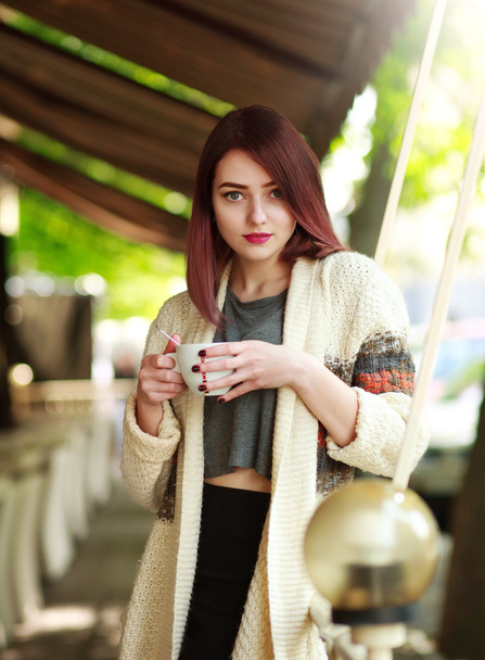 Stylish brunette with cup of coffee on background of summer cafe - Foto, immagini