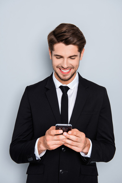 Happy man in black suit typing sms on smartphone - Photo, image