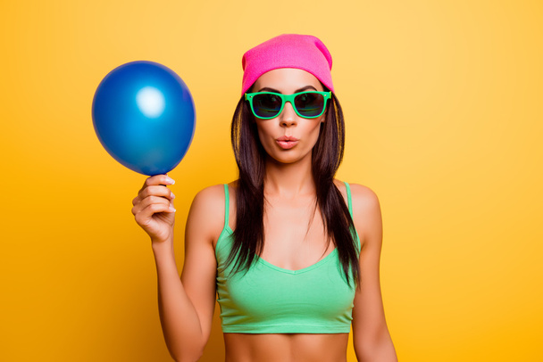 Cheerful hipster girl in pink hat  holding balloon on yellow wal - Fotografie, Obrázek