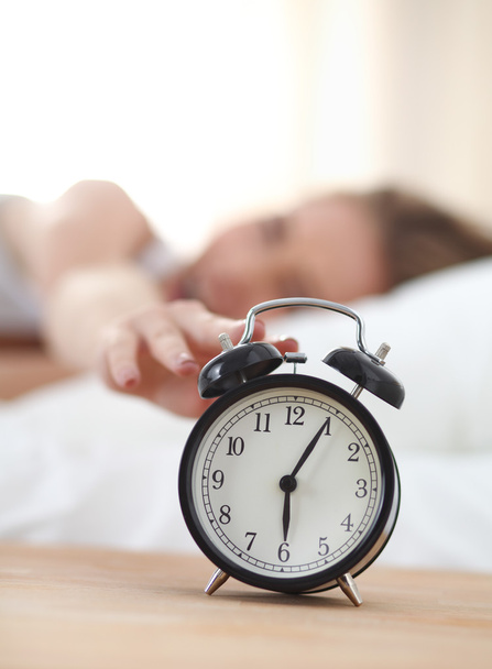 Young sleeping woman and alarm clock in bedroom at home - Photo, Image