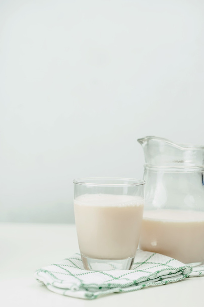 Milk in a glass jug and glass on wooden background - Fotó, kép