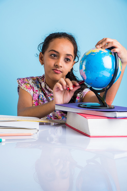 menina indiana estudante olhando para globo educacional e sentado à mesa com livros, caneca de mesa e leite, menina asiática criança estudando geografia, menina asiática curiosa estudando geografia com globo
 - Foto, Imagem
