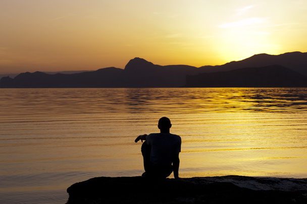 sylwetka człowieka siedzi nad morzem wieczorem - Zdjęcie, obraz