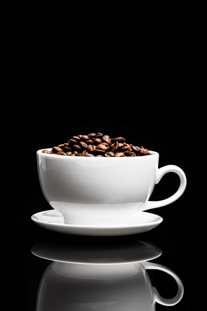 White cup with coffee seeds on black background - Фото, зображення