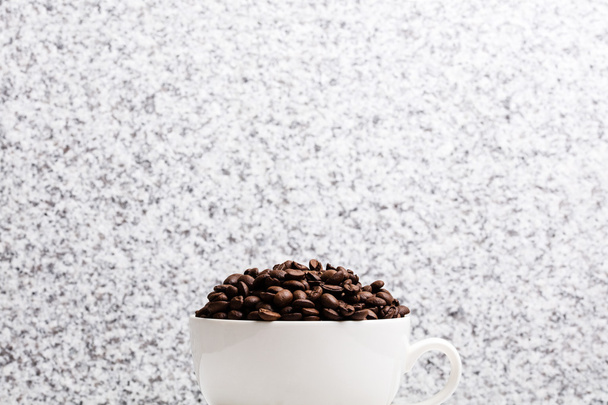 White cup with coffee seeds on granite background - Foto, Imagen