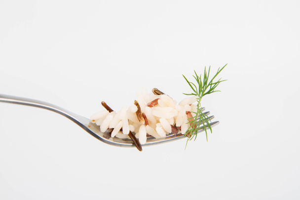 Three color rice on a fork on white background decorated with dill - Foto, Bild