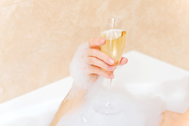 Старшая женщина расслабляется в ванной с бокалом шампанского
 - Фото, изображение