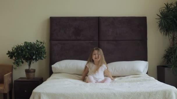 Little girl jumping on the bed at home - Filmmaterial, Video